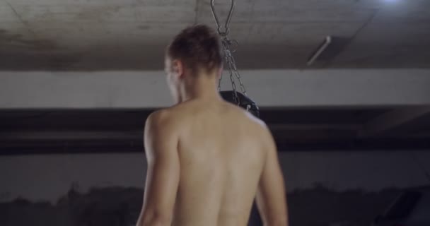 pugile di sesso maschile che colpisce un sacco da boxe enorme in uno studio di boxe. Uomo boxer formazione difficile - Filmati, video