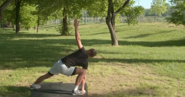 Молодий чоловік робить Йогу розтягуючим у парку зранку. - Кадри, відео
