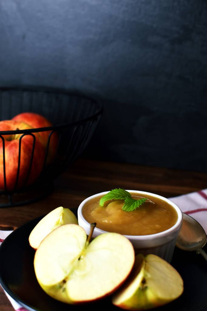 tigela de purê de maçã caseiro com canela e açúcar na tigela cercada por pedaços de maçã na mesa - Foto, Imagem