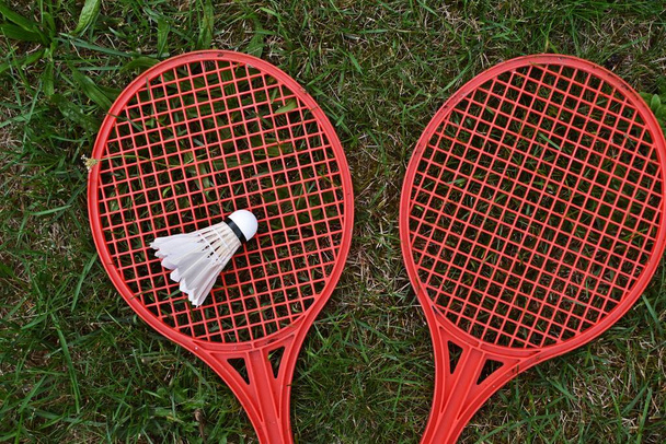 badminton rackets en shuttlecock op groen gras - Foto, afbeelding