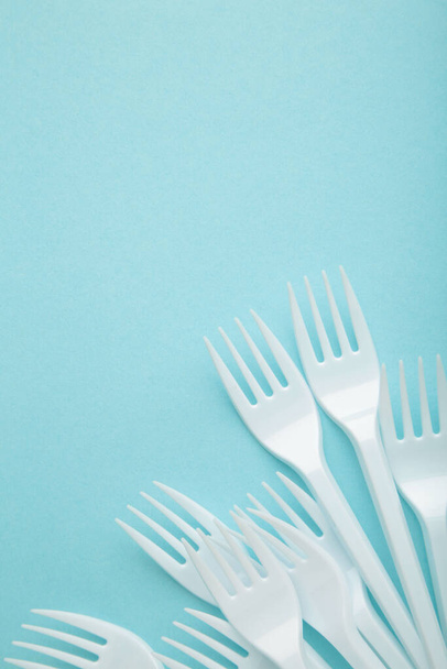 Many plastic forks on a blue background. Top view. - Foto, Imagen