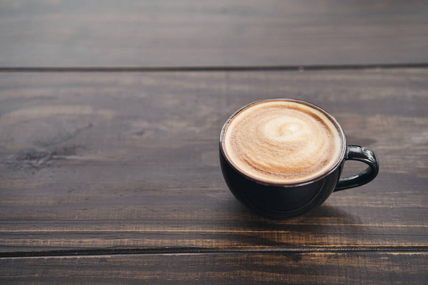 Eine Tasse Kaffee mit Latte Art auf dem Holztisch. Platz für Ihren Text. - Foto, Bild