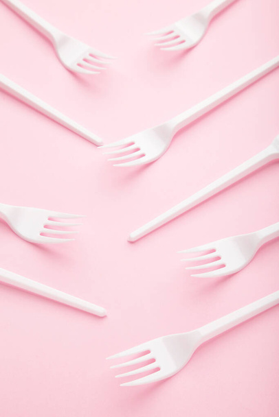 Many plastic forks on a pink background. Top view. - Fotografie, Obrázek