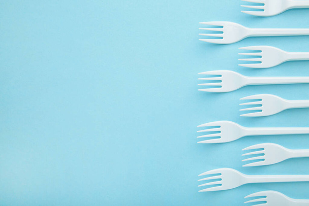 Many plastic forks on a blue background. Top view. - Zdjęcie, obraz