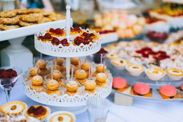 Hochzeitsschokoriegel mit verschiedenfarbigen bunten Cupcakes, Makronen, Kuchen, Gelee und Früchten. - Foto, Bild