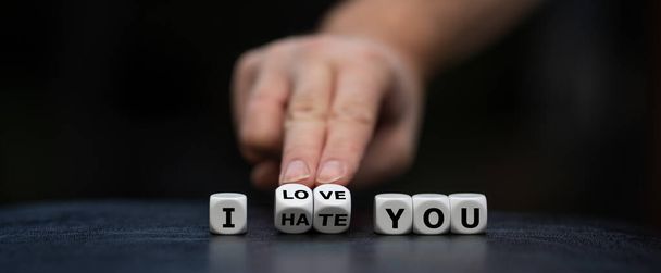 Hand turns dice and changes the expression "I hate you" to "I love you". - 写真・画像