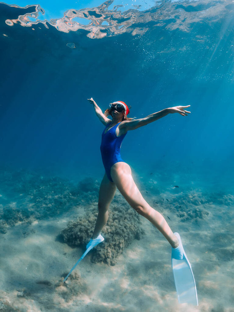 Happy freediver woman with New year cap glides underwater in blue ocean. Christmas holidays concept - Foto, imagen