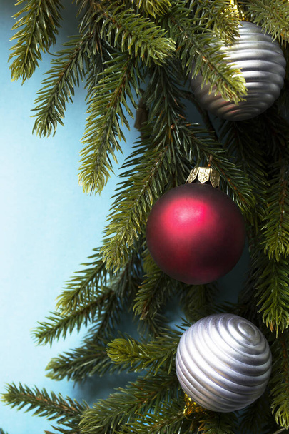 Karácsonyfa ág piros és ezüst golyó közelkép kék háttér - Fotó, kép