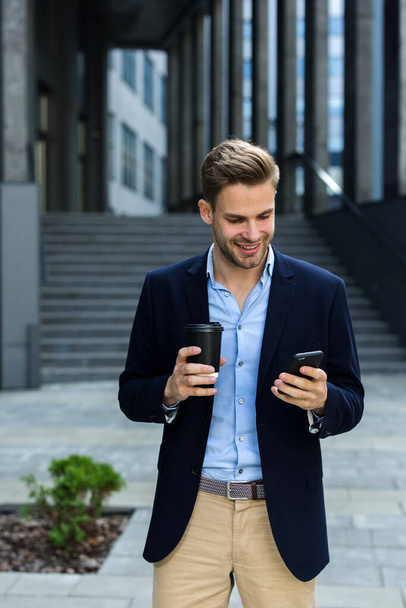 Handsome businessman using smartphone and smiling. Happy young man using mobile phone apps, texting message, browsing internet, looking at smartphone. Young people working with mobile devices - 写真・画像