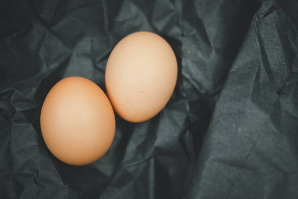 Raw of fresh chicken eggs on a black paper background - Fotografie, Obrázek