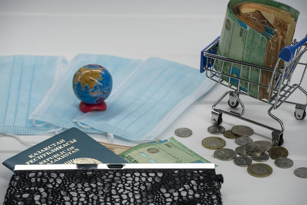 Quarantaine in Kazachstan. Er ligt geld op tafel met medische gezichtsmaskers, een wereldbol, een kaart en een paspoort. De sluiting van grenzen en reizen in Kazachstan. - Foto, afbeelding