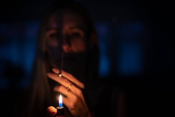 Mid-aged woman lighting a cigarette at home, getting her nicotine daily dose, unable to resist to her unhealthy habit - Foto, imagen