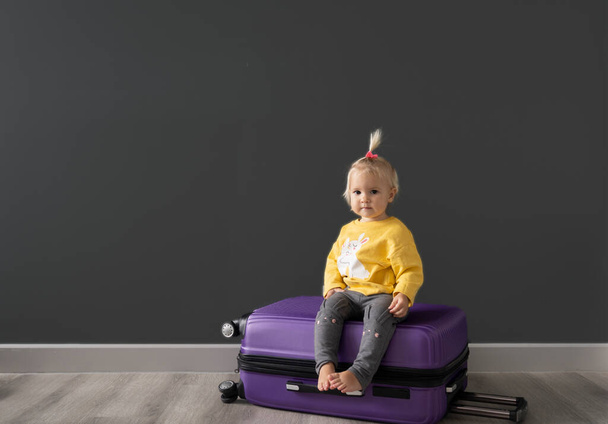 Caucasian cute blond child is sitting at baggage - Photo, image