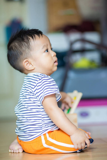 Liebenswerter kleiner Junge spielt hölzernes buntes Spielzeug in lebender Heimkindentwicklung - Foto, Bild