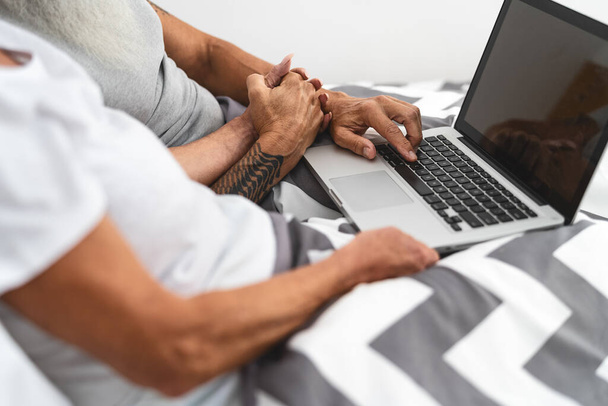 Idős pár hordozható számítógép az ágyban - Idős emberek szórakozás laptop alatt fekvő takarók a hálószobában - Idős szerelem kapcsolat életmód és technológia koncepció - Fotó, kép