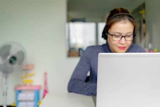 Homályos mosolygós telemarketing ázsiai nő dolgozik otthon. Ázsiai kínai ügyfélszolgálat nő dolgozik otthonról - Fotó, kép
