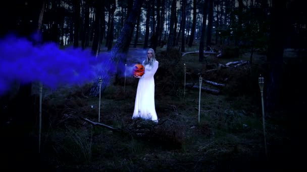 Kaunis blondi nuori tyttö valkoinen mekko tilalla kurpitsa violetti savu - Materiaali, video
