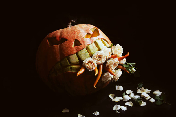 Evil pumpkin devouring flowers and chili peppers. Halloween decor. - Фото, изображение