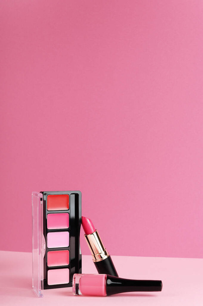 Ajakfény, pirosító paletta, rúzs élénk rózsaszín háttérrel. Dekoratív kozmetikai termékek összetétele és helye szöveg. Sminkcuccok. Divat háttér design másolási hely - Fotó, kép