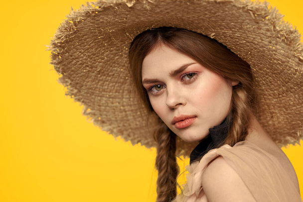 黄色の背景に藁帽子の肖像画の女性は夏のドレスモデルのピグテールロマンスのクロップドビュー - 写真・画像