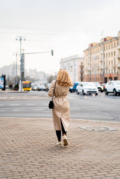 beautiful young woman in a coat and sunglasses walking on the street - 写真・画像