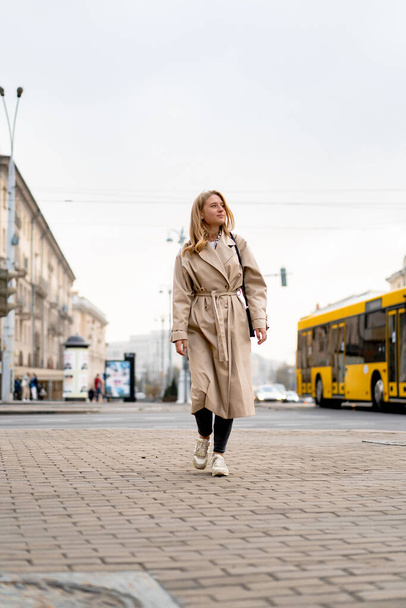 beautiful young woman in a coat and sunglasses walking on the street - Φωτογραφία, εικόνα