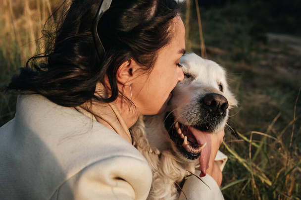 brunette girl hugging white golden retriever in the field - Fotografie, Obrázek