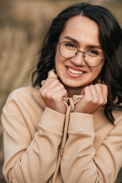 close-up portrait of smiling brunette girl in glasses and hood - Фото, зображення