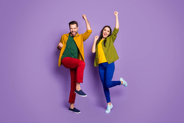 Full size photo two people excited funky lady crazy handsome guy listen good news fists hands raised fans supporters wear casual bright shirts pants outfit isolated purple color background - Fotó, kép