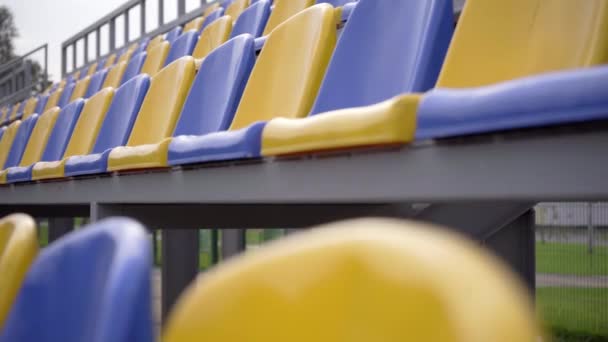 4k, üres műanyag ülések a stadionban. Sorok sárga és kék ülések labdarúgó stadion Tribune nélkül nézők és rajongók - Felvétel, videó