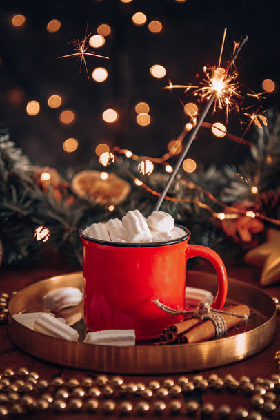  A mug with cocoa with marshmallows in a New Year's setting and a burning sparkler, vertical photo. High quality photo - Foto, Imagem