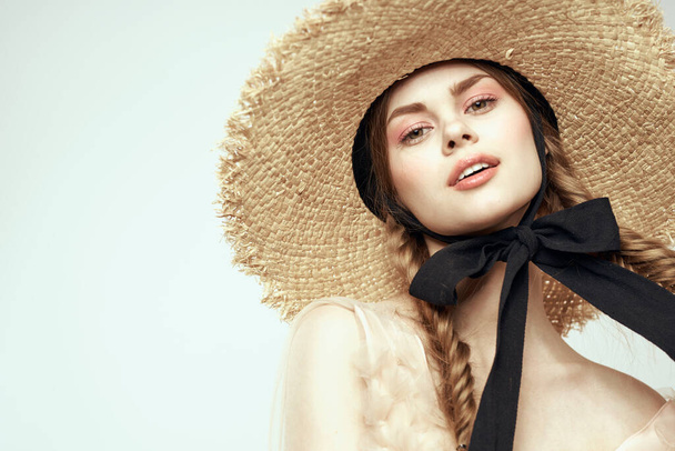 Szép lány egy szalma kalap egy fekete szalag és a ruha egy könnyű háttér romantika modell szórakoztató érzelem - Fotó, kép
