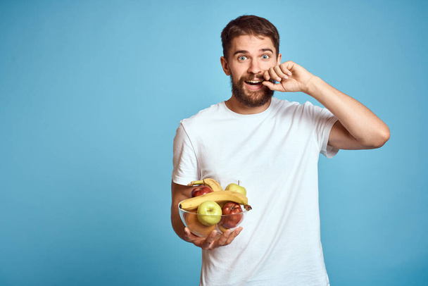 fondo oscuro hombre guapo con una barba sosteniendo fruta fresca y estilo de vida taza transparente - Foto, Imagen