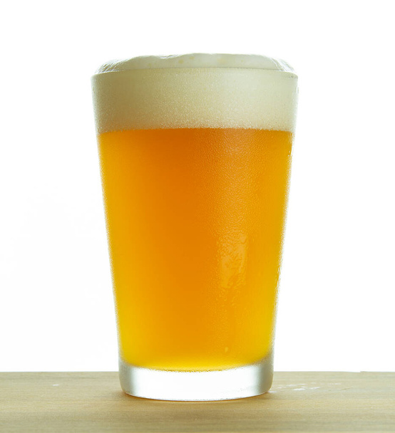 холодне пиво на склянці над дерев'яним столом та білим тлом
. - Фото, зображення