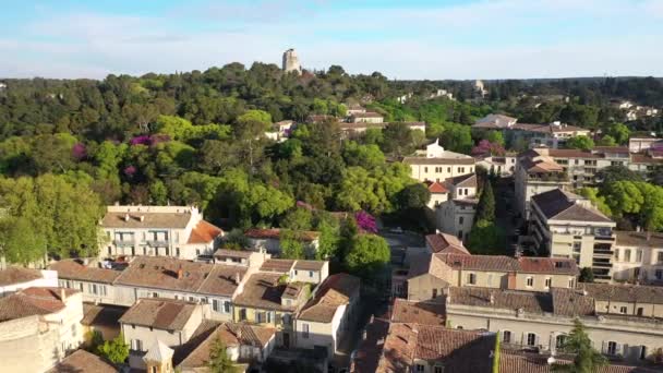 Back aerial traveling over Jardins de la Fontaine public park in Nimes Tower Magne in background spring sunny day green leaves on trees - Footage, Video