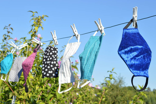 a lot of different self made corona face masks out of fabric hanging on a clothesline for drying - Photo, Image