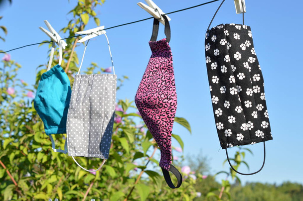 a lot of different self made corona face masks out of fabric hanging on a clothesline for drying - Photo, Image