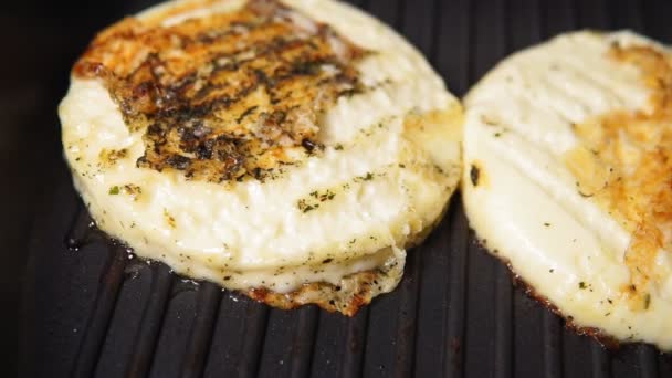 gegrilde haloumi kaas wordt gegrild op een donkere metalen grill pan in close-up - up. - Video