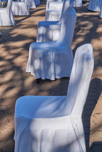 Gran grupo de sillas blancas vacías dispuestas para la distancia social, listo para sentar a los visitantes a la conferencia de negocios al aire libre. COVID-19 medidas de salud y seguridad durante la pandemia requieren el espaciamiento entre las personas - Foto, imagen