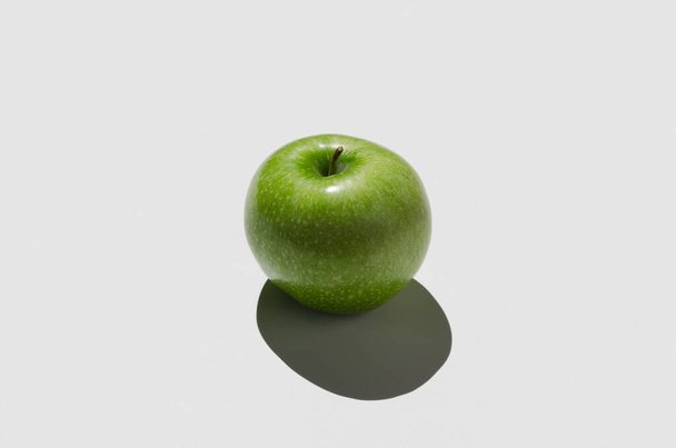 Green apple on a white background. Hard shadow. - Valokuva, kuva