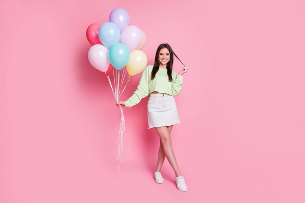 Full length photo of cheerful dreamy youngster girl touch haircut hold air balloons want attract boys birthday event wear green pullover white clothes isolated pastel color background - Fotó, kép