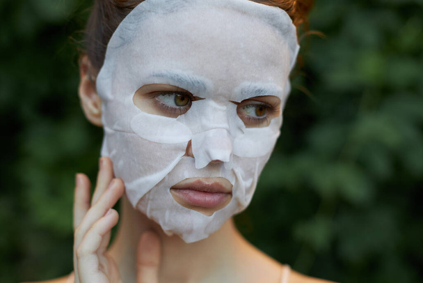 Nette Frau kosmetische Maske sieht zur Seite und berührt einen Finger in der Nähe des Gesichts nackten Schultern  - Foto, Bild