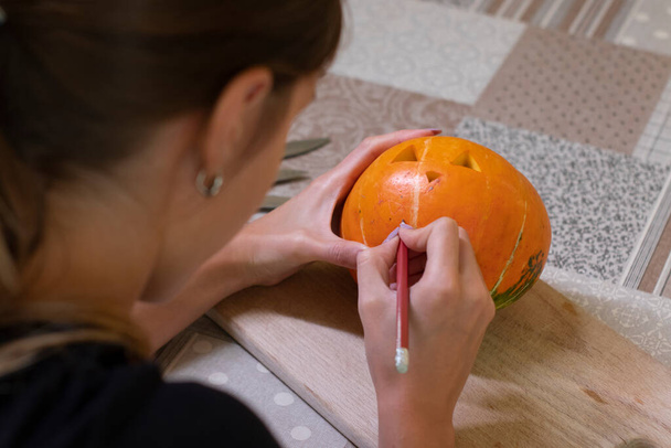 der Prozess der Herstellung eines Halloween-Kürbisses. Zeichnung eines Layouts eines brünetten Mädchens. Horror-Thema und Halloween - Foto, Bild