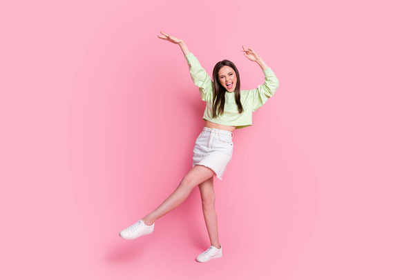 Full size photo of attractive funky lady excited dance disco hit youth party dancer wear casual green crop pullover naked belly jeans short skirt shoes isolated pink pastel color background - Fotó, kép