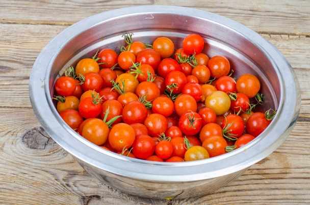 Small ripe red cherry tomatoes in metal bowl on wooden table. Studio Phot - Photo, Image