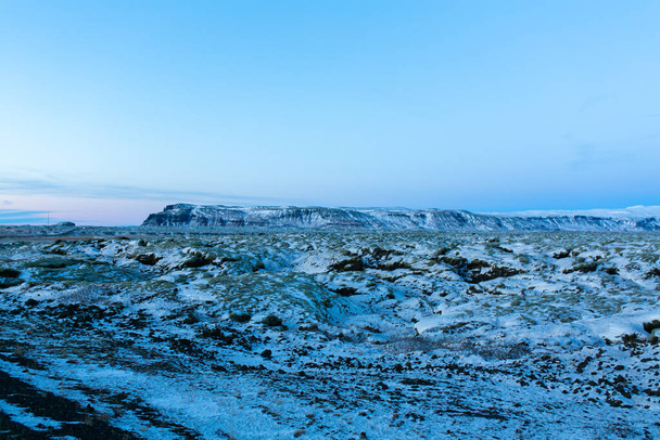 Winter landscape in Iceland. A field of solidified lava covered with moss is covered with snow - 写真・画像
