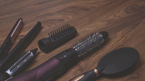 Hairdressing tools on a wooden background. Combs and hair dryer, hair straightener. Long hair curls. Extension hair care. - Foto, imagen