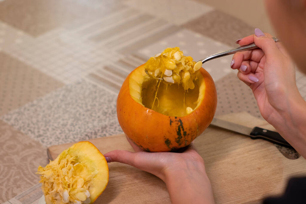 el proceso de hacer una calabaza de Halloween. limpieza de semillas por una chica morena. tema de terror y Halloween - Foto, Imagen