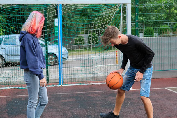 Teenagers boy and girl playing street basketball together - Photo, image