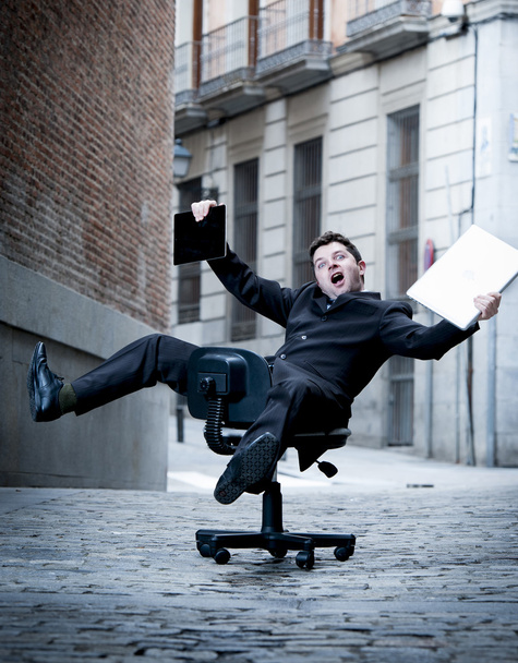  hombre de negocios rodando cuesta abajo en silla con computadora y tableta
 - Foto, Imagen